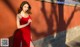 a woman in a red dress leaning against a wall