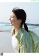 A woman standing on a beach next to the ocean.