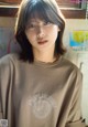 A young woman wearing a brown shirt with a logo on it.