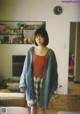 A woman standing in a living room next to a couch.