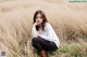 A woman sitting in a field of tall grass.