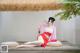 A woman in a red dress sitting on a wooden platform.