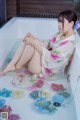 A woman sitting in a bathtub filled with flowers.