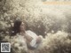 A woman laying in a field of white flowers.