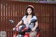 A woman sitting on a red motorcycle wearing a helmet.