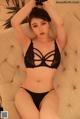 A woman in a black lingerie sitting on a couch.