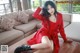 A woman in a red dress sitting on a coffee table.